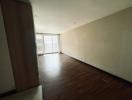 Spacious unfurnished living room with large window and hardwood flooring