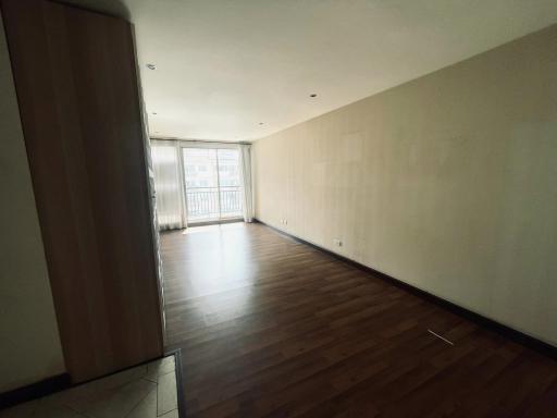 Spacious and well-lit empty living room with hardwood floors and large windows