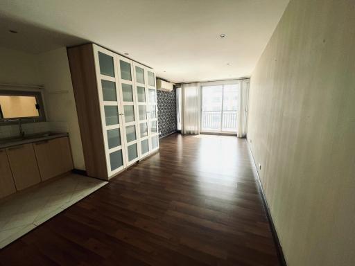 Spacious open-plan living area with kitchen, wooden flooring, and balcony access