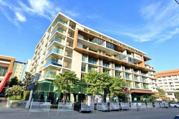 Modern multi-story apartment building with balconies and ground floor commercial spaces