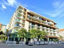 Modern multi-story apartment building with balconies and ground floor commercial spaces