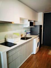 Modern compact kitchen with white cabinets and stainless steel appliances