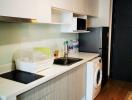 Modern compact kitchen with white cabinets and stainless steel appliances