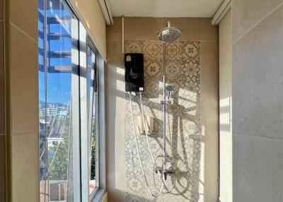 Modern bathroom with shower, beige tiles, and natural light