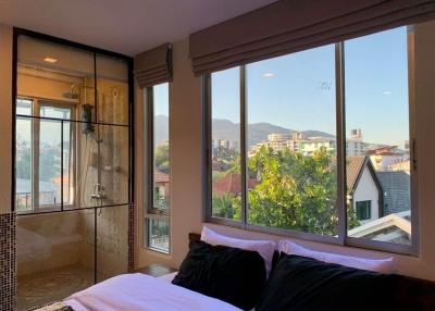 Cozy bedroom with natural lighting and scenic view through large windows