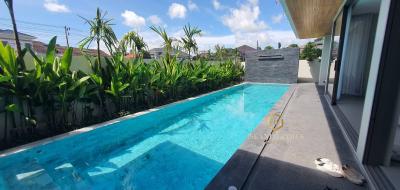 Private outdoor swimming pool surrounded by lush greenery with clear skies
