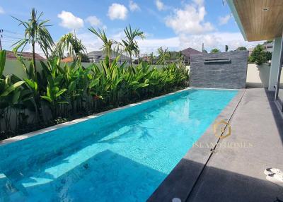 Private outdoor swimming pool surrounded by lush greenery with clear skies
