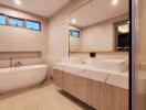 Modern spacious bathroom with a freestanding tub, large mirror, and elegant finishes