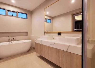 Modern spacious bathroom with a freestanding tub, large mirror, and elegant finishes