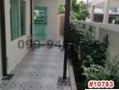 Exterior view of the building entrance with patterned tile flooring and greenery