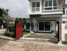 Front view of a modern two-story house with a red gate and driveway