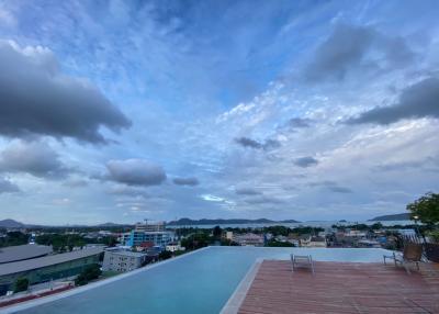 Rooftop infinity pool with panoramic city and mountain views under a dramatic sky