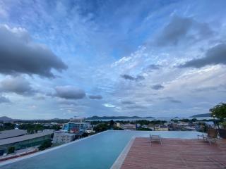 Rooftop infinity pool with panoramic city and mountain views under a dramatic sky