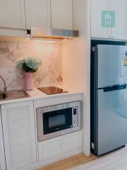 Modern kitchen with microwave, refrigerator, and marble countertop