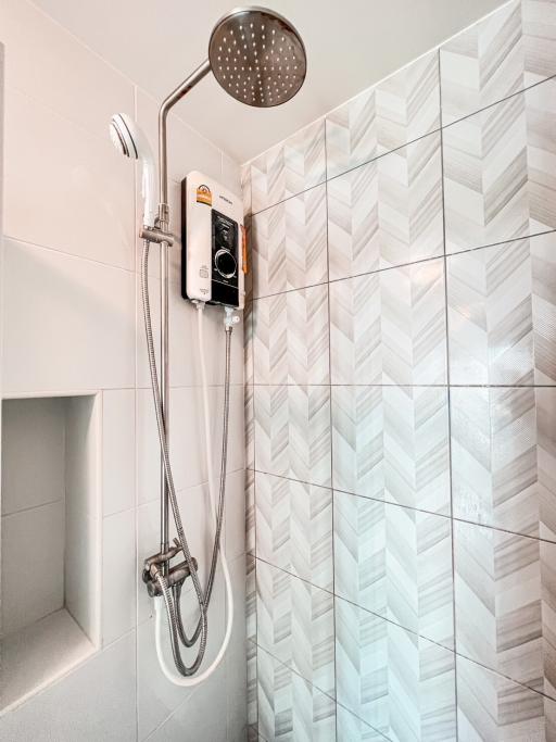 Modern bathroom with wall-mounted shower and white patterned tiles