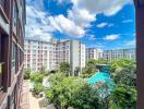 Bright sunny view from an apartment balcony showcasing the complex's swimming pool and garden area