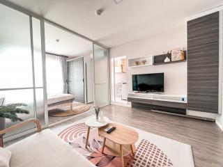 Modern bedroom with living space, featuring a large bed, mirrored wardrobe, and flat-screen TV