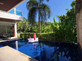 Backyard with a swimming pool, outdoor seating, and lush landscaping