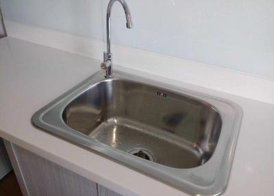 Stainless steel kitchen sink with modern faucet in a white countertop