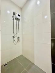 Modern white tiled bathroom with an electric shower unit