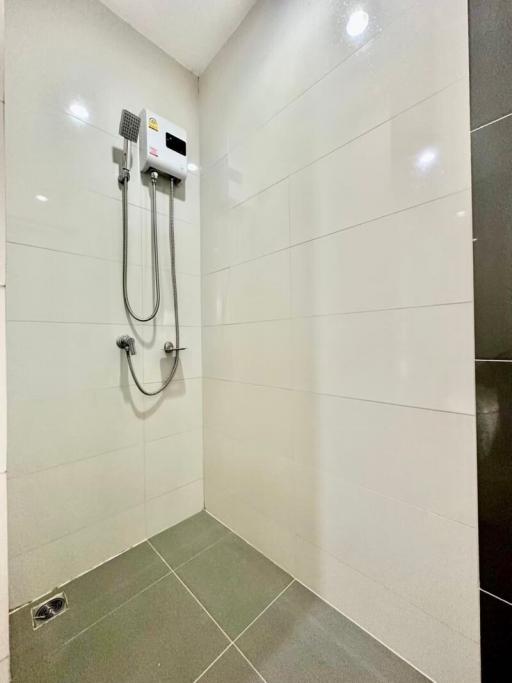 Modern white tiled bathroom with an electric shower unit