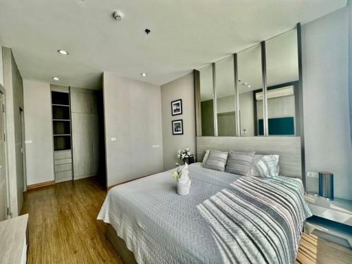 Spacious modern bedroom with large mirror wardrobe and hardwood floors