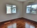 Empty bedroom with wooden floor and natural light