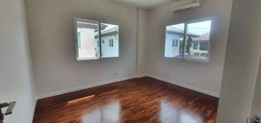 Empty bedroom with wooden floor and natural light