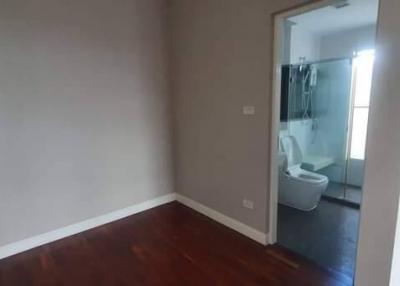 Empty bedroom with polished wooden floor and open bathroom door