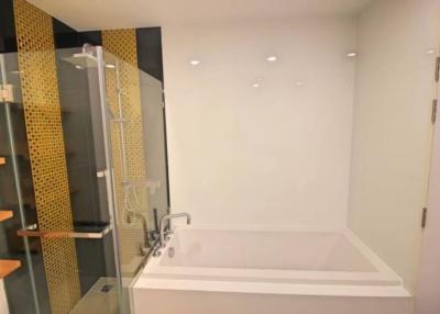 Modern bathroom with gold-accented shower tiles and luxury bathtub