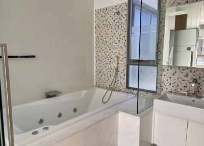 Spacious modern bathroom with a bathtub and mosaic tiles
