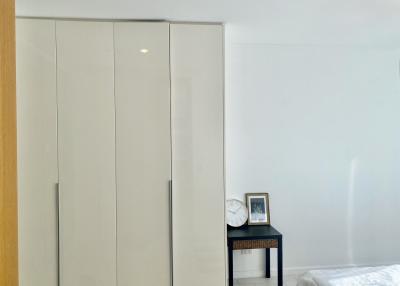 Minimalist bedroom with large white wardrobe and bedside table