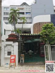 Urban building exterior with tropical plants and commercial signage