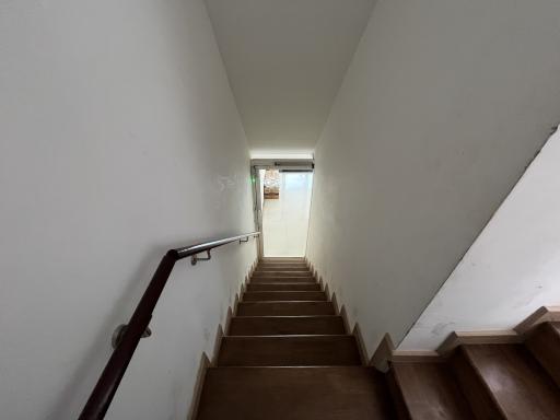 Interior view of a staircase leading upstairs with wooden steps and white walls