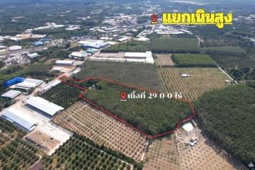 Aerial view of a large plot of land available for sale with marked boundaries near industrial facilities