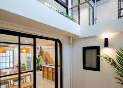 Interior view of a modern two-story home with open space design, showcasing the dining area, staircase, and upper-level balcony