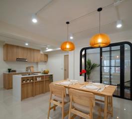 Modern kitchen and dining area with wooden furniture and elegant pendant lights