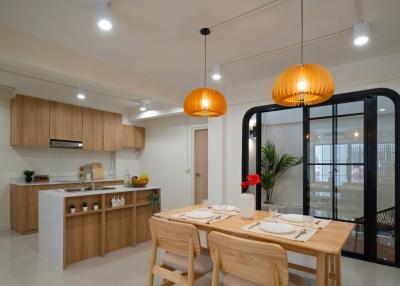 Modern kitchen and dining area with wooden furniture and elegant pendant lights