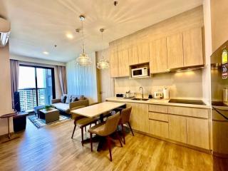 Modern open-plan kitchen with living area featuring elegant pendant lighting and a balcony