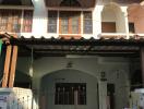 Two-story house facade with gabled roofing and gated entrance