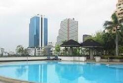 Residential building complex with a large outdoor pool and city skyline in the background