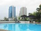 Residential building complex with a large outdoor pool and city skyline in the background