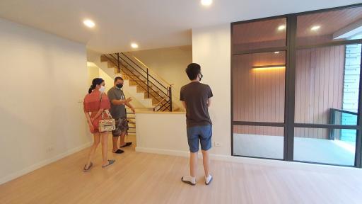 People standing in a spacious living room with large window and staircase