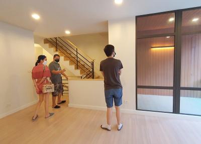 People standing in a spacious living room with large window and staircase