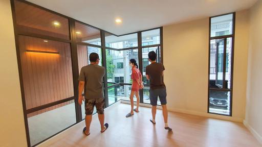 Prospective buyers touring a spacious living room with large windows and adjacent balcony