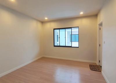 Spacious empty bedroom with large window and hardwood floors