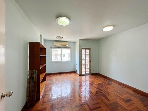 Spacious bedroom with wooden flooring, natural light and air conditioning