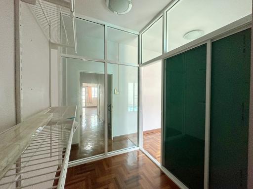 Interior view of a space with glass room dividers, wooden flooring, and balcony access