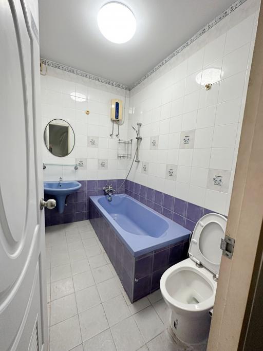 Compact bathroom with blue and white tiles and fixtures including a bathtub, toilet, and sink