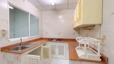 Compact kitchen with tiled walls, basic appliances, and wooden cabinetry